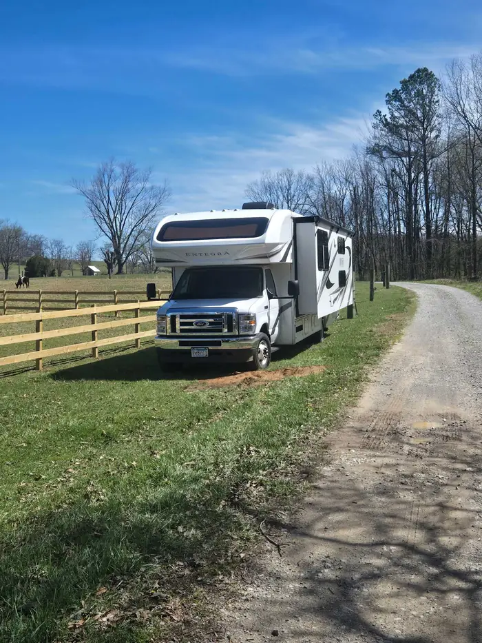 A motorhome pitched beside the pasture fence on the farm lane